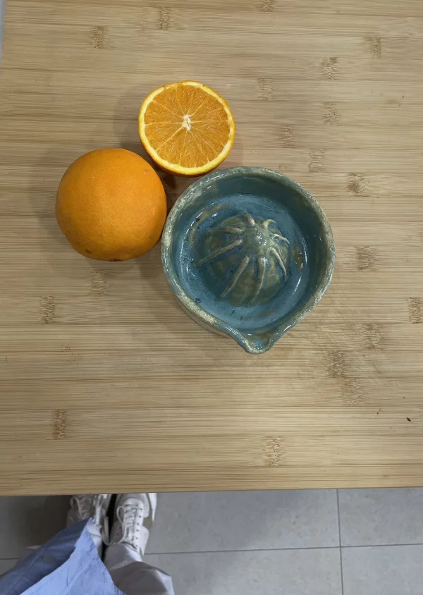 Exprimidor en la encimera con naranjas apunto de exprimir