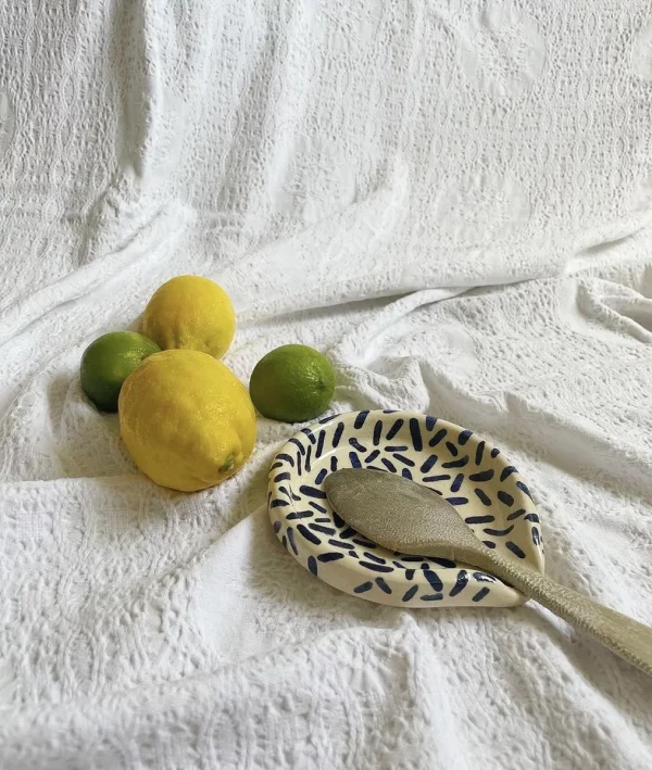 Bodegón de soporte de cuchara para cocinar hecho con cerámica de manera artesanal con limones y lima