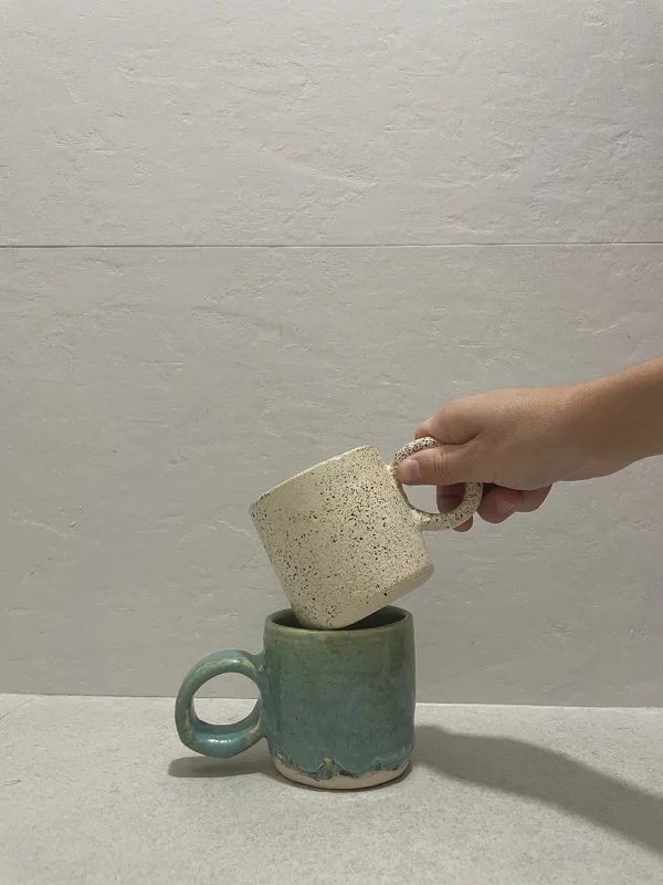 Ceramista coge por el asa una de las dos tazas que ha realizado de manera artesanal